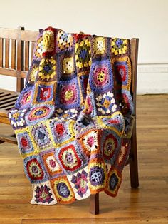 a crocheted blanket sitting on top of a wooden chair next to a bench