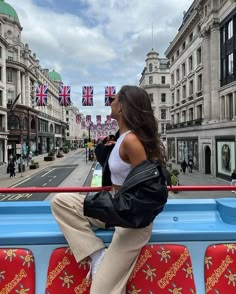 a woman sitting on the back of a blue and red bus in london, england