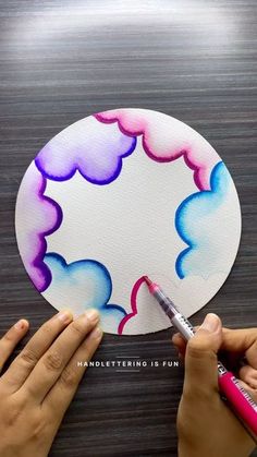 someone is painting the clouds on a paper plate with watercolors and crayons