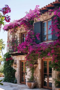 an old stone building with purple flowers growing on it's windows and balconies