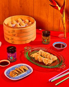 a table topped with lots of food and chopsticks next to a bowl filled with sauce