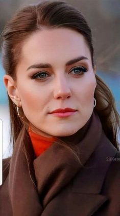 a woman with blue eyes wearing a brown coat