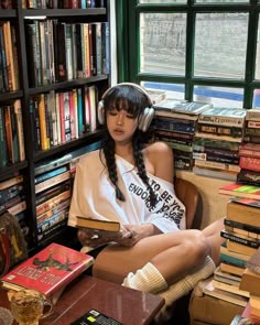 a woman sitting in a chair with headphones on her ears and books behind her