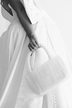 Enhance your bridal experience with the Camilla Purse. Adorned with lustrous pearl beads, this luxurious bag adds a touch of elegance to any wedding look. Details: Width: 10 inches Length: 6.5 inches without straps, 11.5 inches with straps ﻿Not lined Ivory Faux pearls Final Sale