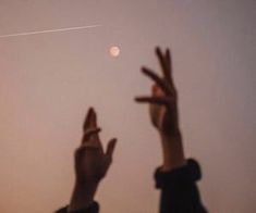 two people reaching up to the moon with their hands