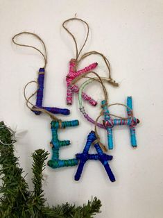 three ornaments are hanging on the wall next to a christmas tree and pine branches with twine