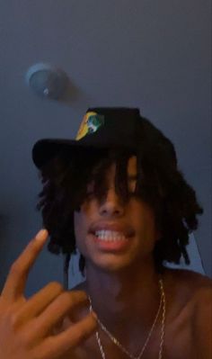 a young man wearing a hat and making the peace sign