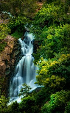 a large waterfall surrounded by lush green trees