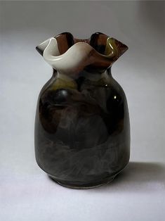 a black and white vase sitting on top of a table next to a white wall