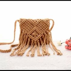 a crocheted bag with tassels and flowers on the ground next to it