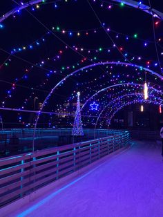 people skating on an ice rink at night with christmas lights all over the walkways