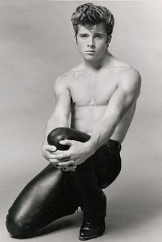 black and white photograph of a shirtless man holding a bowling ball