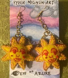 two yellow sun and moon shaped earrings on a green cloth with an advertisement for eye of azure