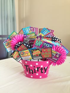 a pink polka dot bucket filled with lots of candy and candies on top of a table