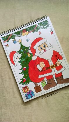 a drawing of santa claus next to a christmas tree on a sheet of paper,