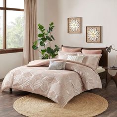 a bed in a bedroom with pink comforter and pillows