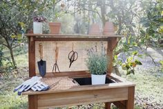 a wooden bench with potted plants and gardening utensils