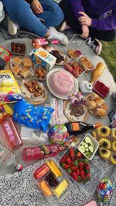 two women sitting on the ground with food and snacks laid out in front of them