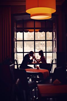 two people sitting at a table in front of a window