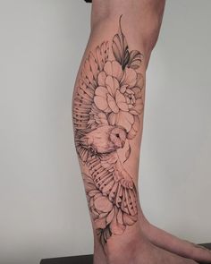 a woman's leg with a bird and flowers tattoo on it