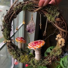 a hand holding a wreath with two mushrooms on it and moss growing in the middle