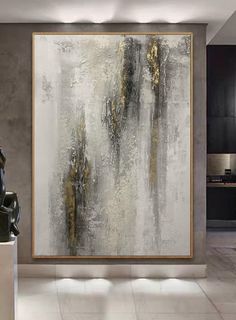 an abstract painting hangs on the wall in a modern living room with white and gold accents