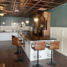 an empty kitchen with bar stools in the center and wood flooring on the other side