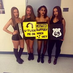 three girls are standing in front of a wall holding signs and posing for the camera