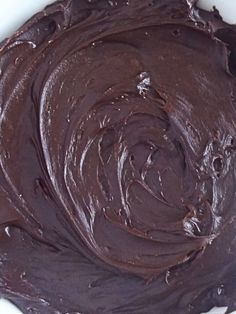 a white bowl filled with chocolate frosting on top of a table