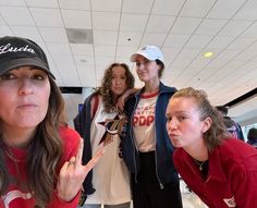 three women are standing in an airport and one is making the peace sign with her hand