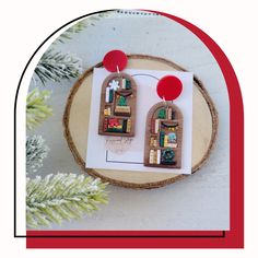 the earrings are made out of wood and have colorful designs on them, along with red balls