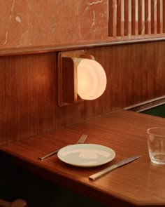 a table with a plate, fork and knife next to a light on the wall