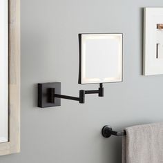 a bathroom mirror mounted to the side of a wall next to a towel rack with a light on it