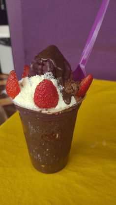 an ice cream sundae with chocolate, strawberries and whipped cream on top sitting on a table