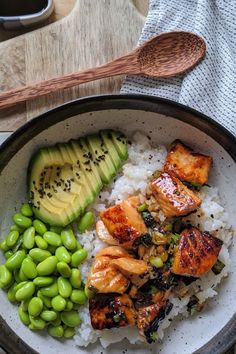 a bowl filled with rice, meat and vegetables next to an avocado slice