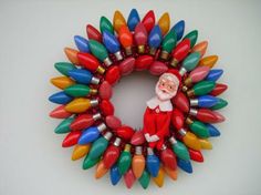 a wreath made out of christmas lights with santa clause on top and red, green, yellow, orange, and blue decorations