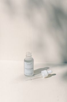 a bottle of medicine sitting on top of a white table next to a dropper