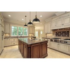 a large kitchen with an island in the middle and two lights hanging from the ceiling