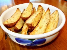 a white bowl filled with sliced potatoes on top of a wooden table