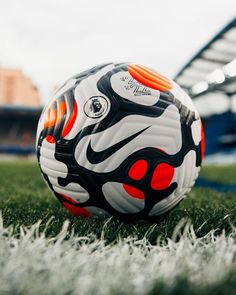 a soccer ball sitting on top of a lush green field next to an empty stadium