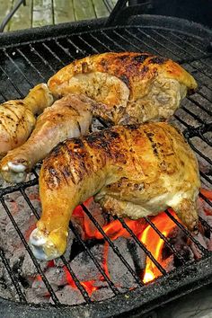 two chicken legs are cooking on the grill