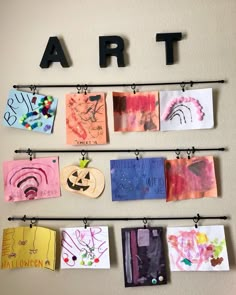 art is hanging on the wall in front of children's drawings and paintings, including pumpkins