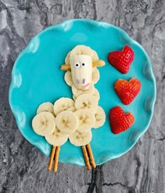 a plate with bananas, strawberries and a sheep made out of fruit on it