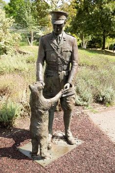 a statue of a man in uniform holding a cat on top of a cement slab