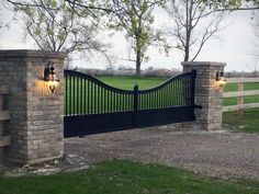 an iron gate with two lights on each side and a brick pillar at the end