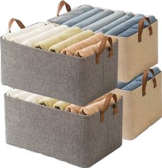 three storage bins with handles are stacked on top of each other and one is filled with folded fabric