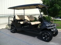 a black golf cart parked in front of a building with two seats on the back