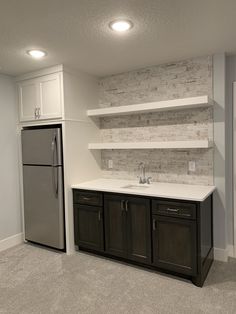 an empty kitchen with stainless steel appliances and white counter tops, along with shelving on the wall