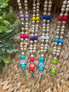 several necklaces with wooden beads hanging on a wall next to a potted plant