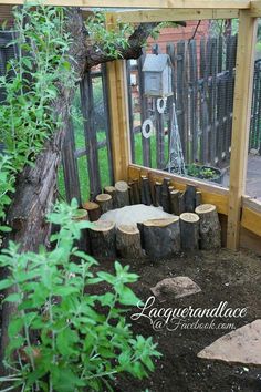 an outdoor area with logs and plants in the ground next to a fenced in area